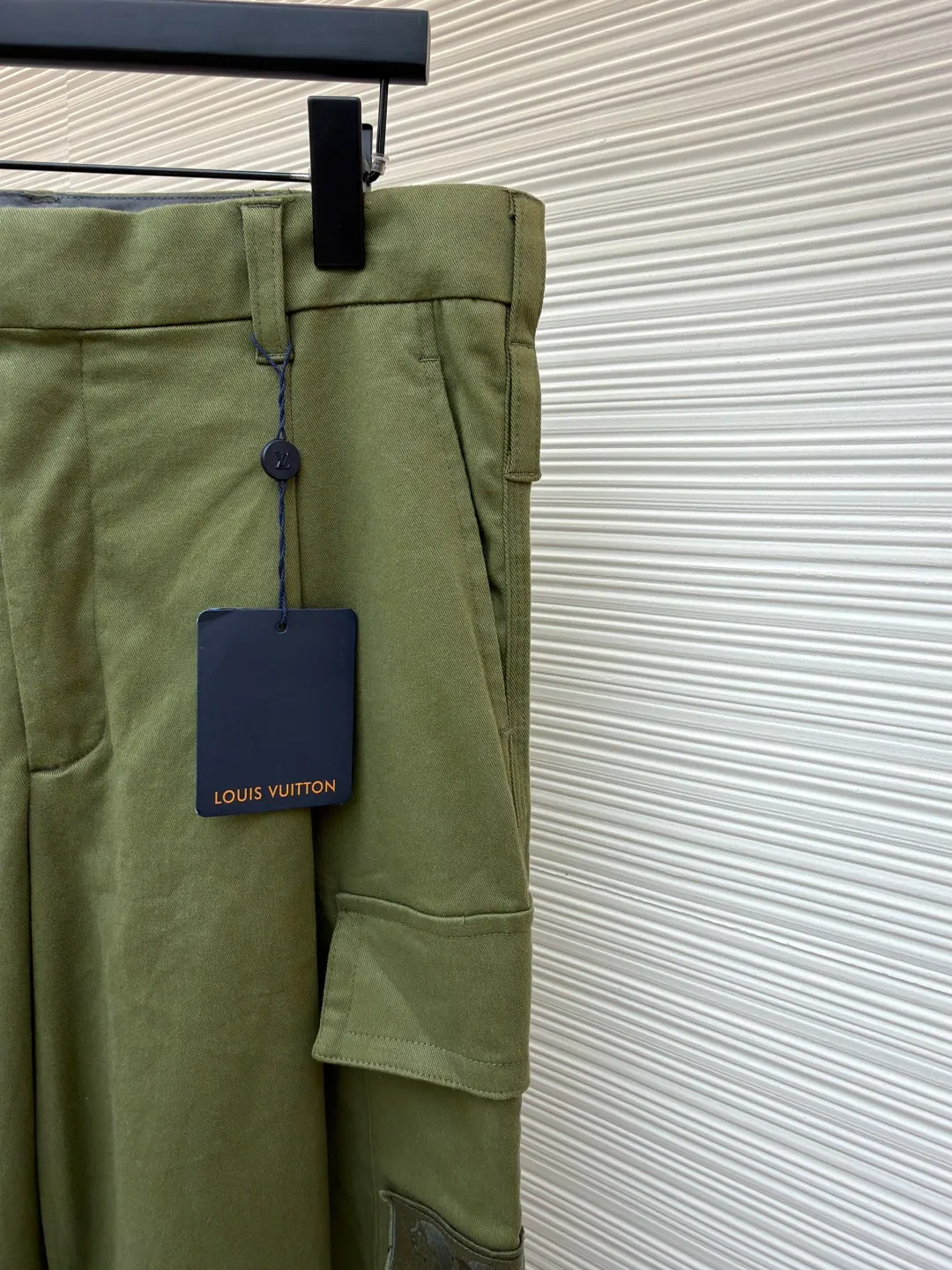 LOUIS VUITTON portrait embroidered work trousers ●Item number: 1681219-B65 ●Material: cotton twill fabric ●Technology: embroidery production ●Color: green ●Version: fitted version ●Weight: about 655 grams ●Size: 44-46-48-50 ●Description: The high cotton content ensures the fabric's excellent breathability, durability and classic workwear texture, while the twill weave gives it unique wear resistance and stiffness. The special fabric technology solves the pain points of tight and stiff traditional overalls; it provides greater freedom when moving, significantly improves wearing comfort and flexibility, and achieves a balance between function and comfort. For the embroidered portrait patch on the left, the portrait is digitally processed and converted into a line drawing blueprint that can be embroidered. A high-precision computer embroidery machine is used to perform multi-layer embroidery, and the outline, light and shade and texture details of the portrait are created by interweaving and superimposing embroidery threads of different colors. Tens of thousands of stitches and fine color transitions ensure clear lines and no unnecessary threads, making the portrait lifelike and three-dimensional. The design of the trousers combines retro workwear genes with modern deconstruction. The core lies in the neat pleat processing, which not only deconstructs the flat silhouette of the front, increases the three-dimensional sense and design level, but also visually optimizes the leg lines. Multiple flap pockets are classic workwear functional elements and the overall tough style. The overall wiring is straight and delicate, the fabric is comfortable and soft, and the color is consistent without color difference. It can be matched with the same style to create a fashionable look and control various occasions. Customized accessories, complete with three standards, same style for men and women!